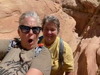 Two women are taking a selfie in front of a rock formation.