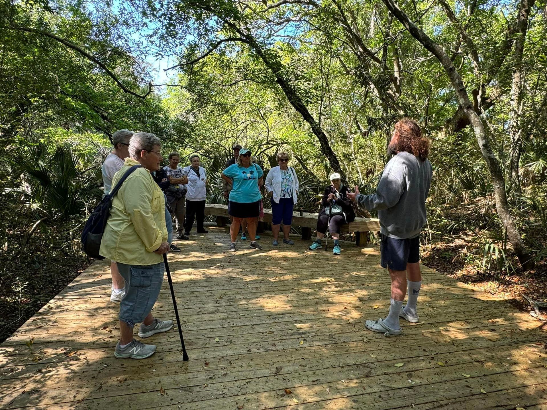 A group of people are standing on a wooden deck in the woods.