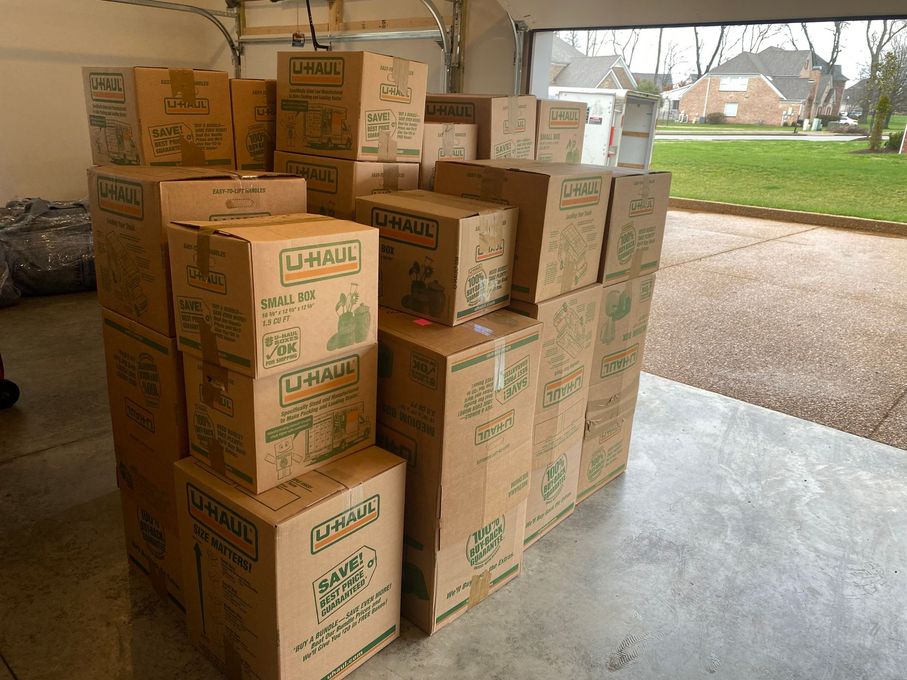 A stack of U-Haul moving boxes in a garage, ready for transport.