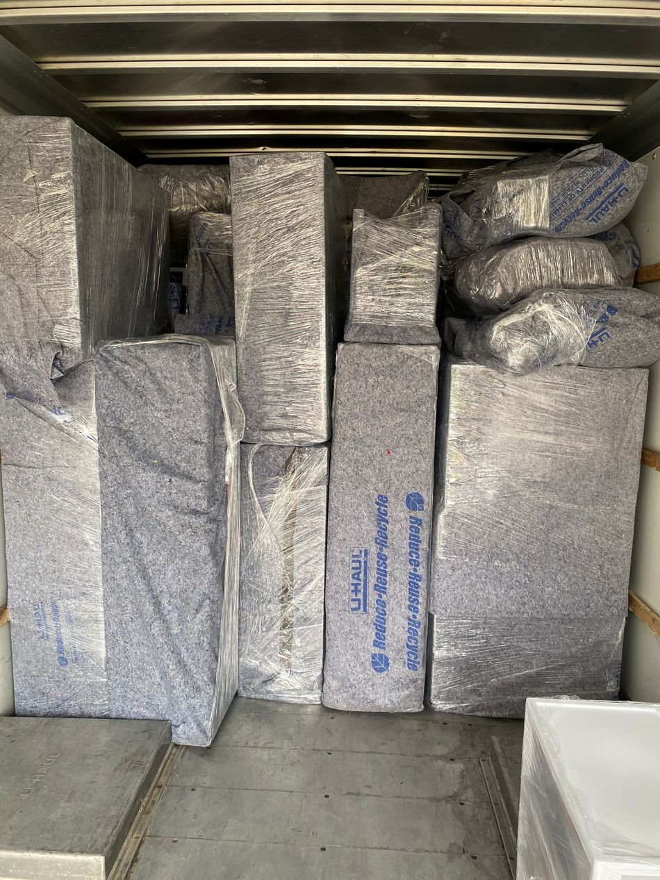 Boxes of construction material, wrapped in blue protective plastic, fill a truck.
