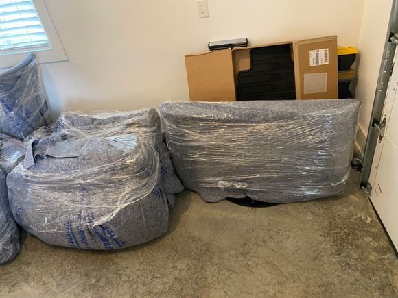 Wrapped furniture and boxes in a garage.