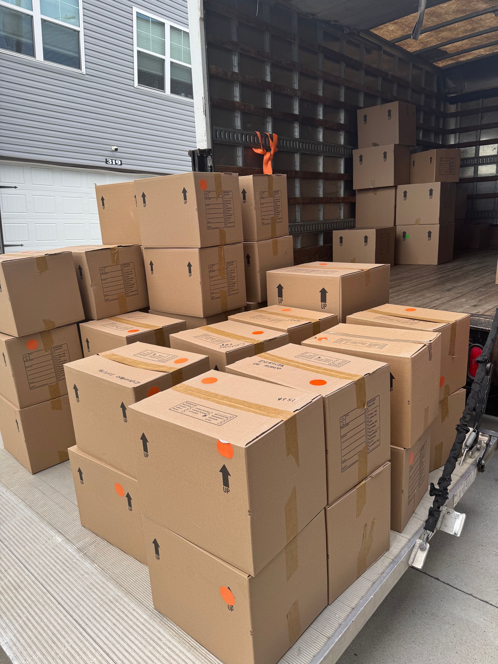 Boxes stacked in a moving truck; residential area in the background.