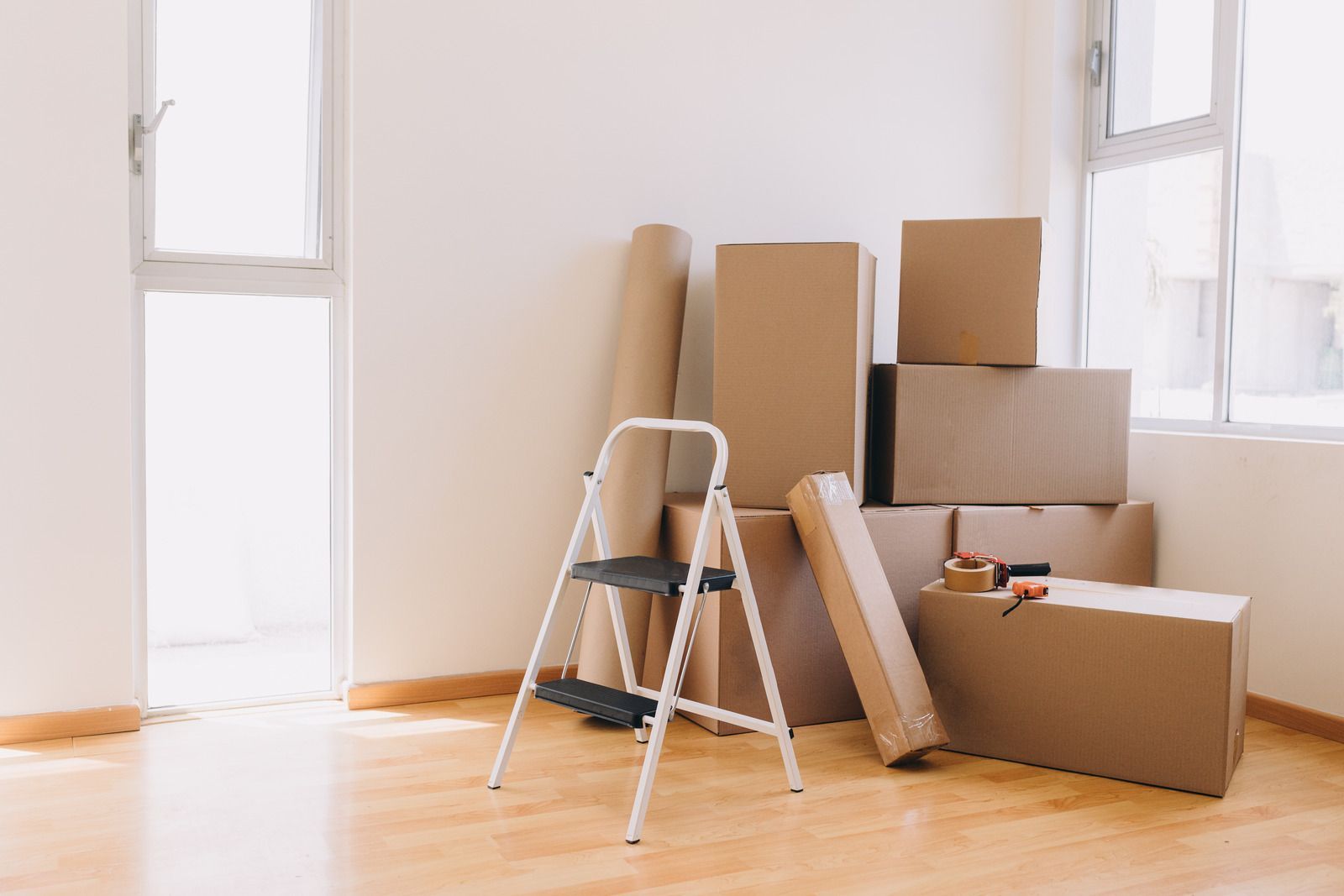 Cardboard boxes stacked in a room with a stepladder, ready for moving.
