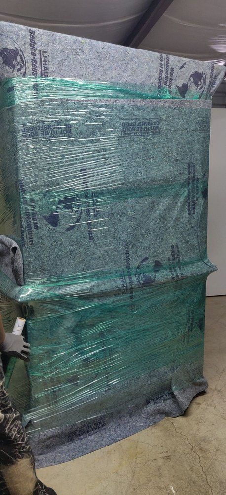 A large, wrapped package, possibly furniture, in a warehouse setting.