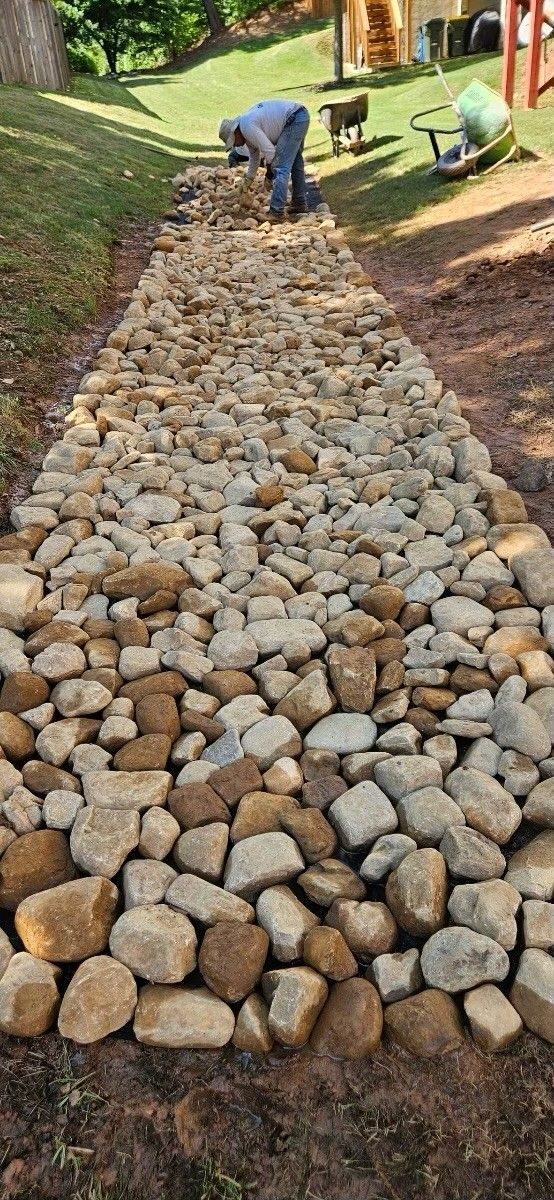 A man is working on a path made of rocks.