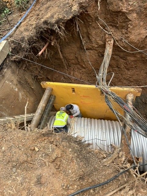 A man is working on a pipe in a hole in the ground.