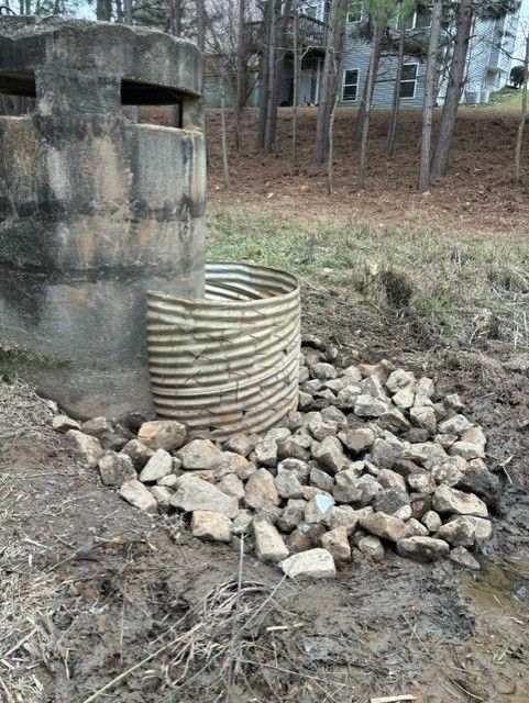 A concrete structure is sitting next to a pile of rocks.