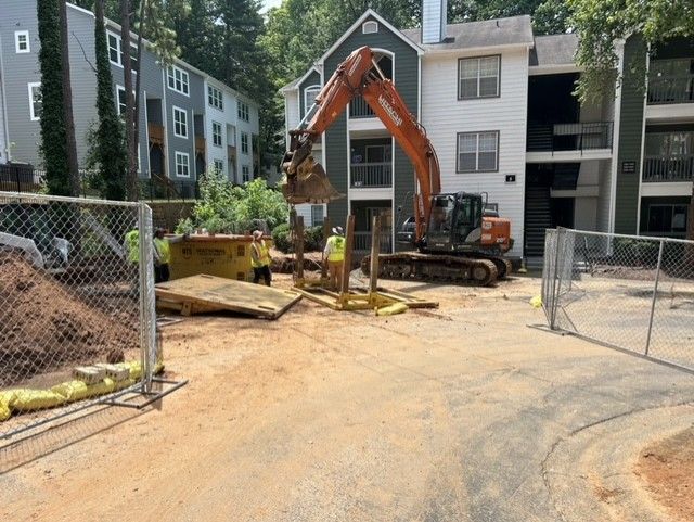A large excavator is working on a construction site in front of a building.