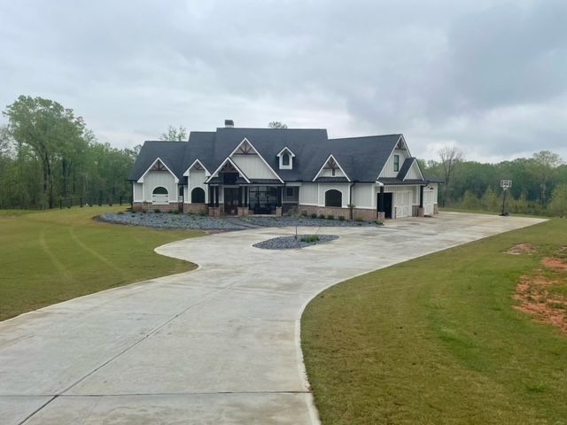 A large white house with a black roof is sitting on top of a lush green field.