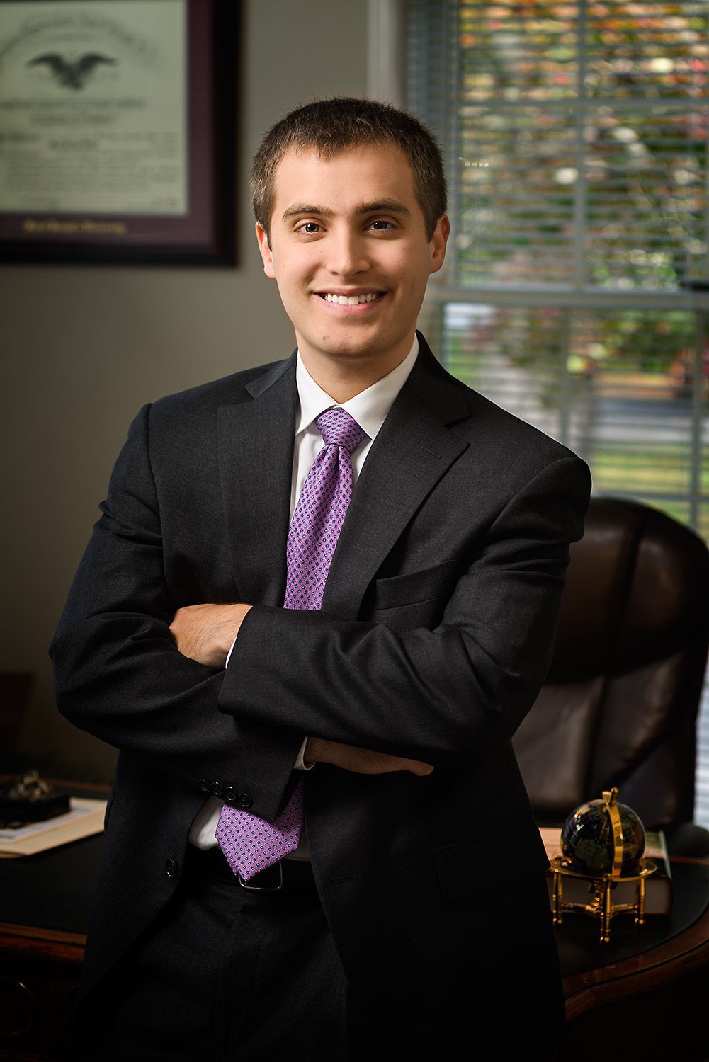 Man in a suit and tie smiles, possibly a professional headshot.
