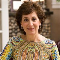 A woman in a blue jacket and white shirt is smiling for the camera