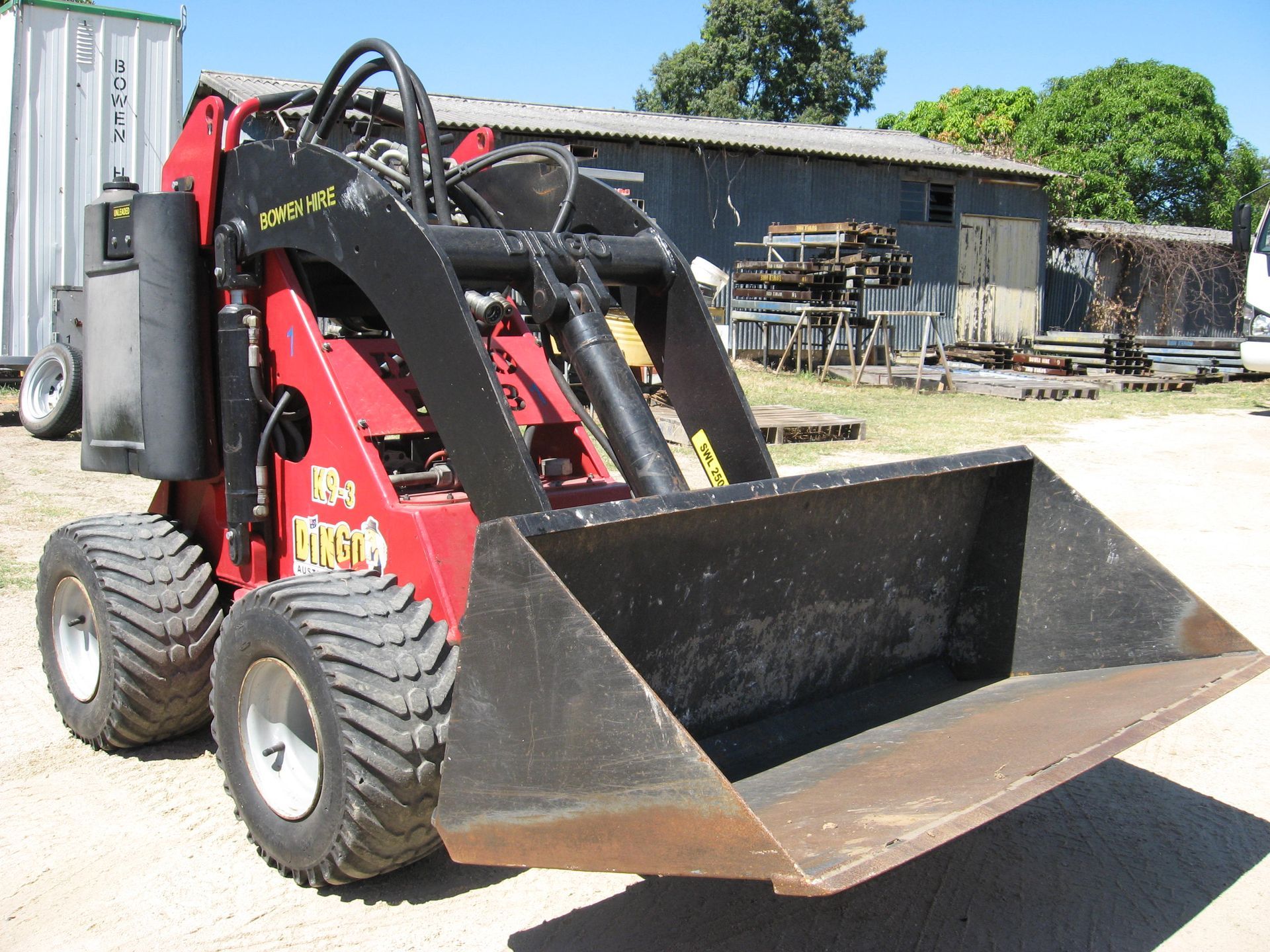 Red Skid Steer Loader with Front Bucket Parked Outdoors — Bowen Hire in Proserpine, QLD