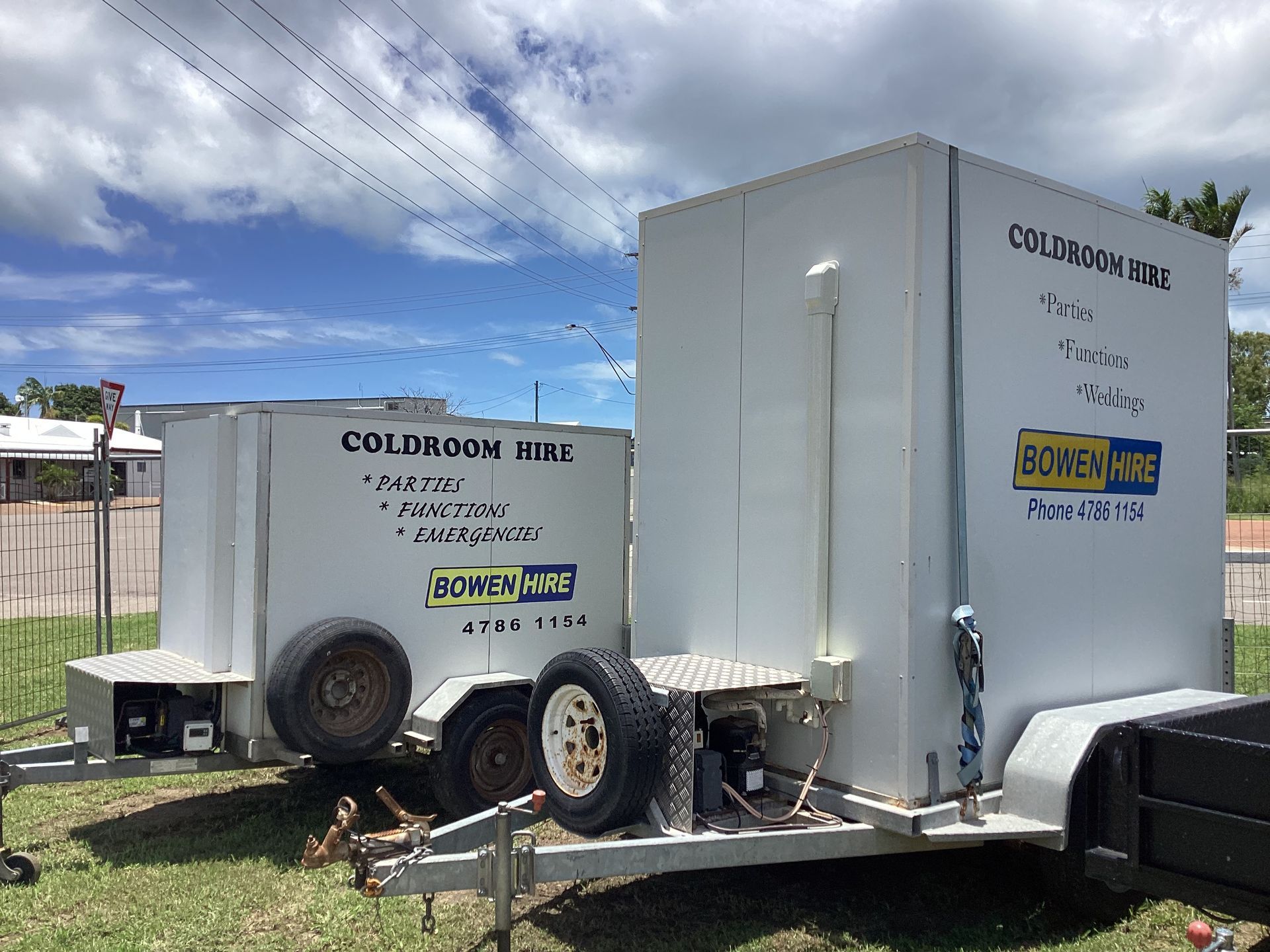 Two White Enclosed Utility Trailers Parked on Grass Under a Cloudy Sky — Bowen Hire in Bowen, QLD