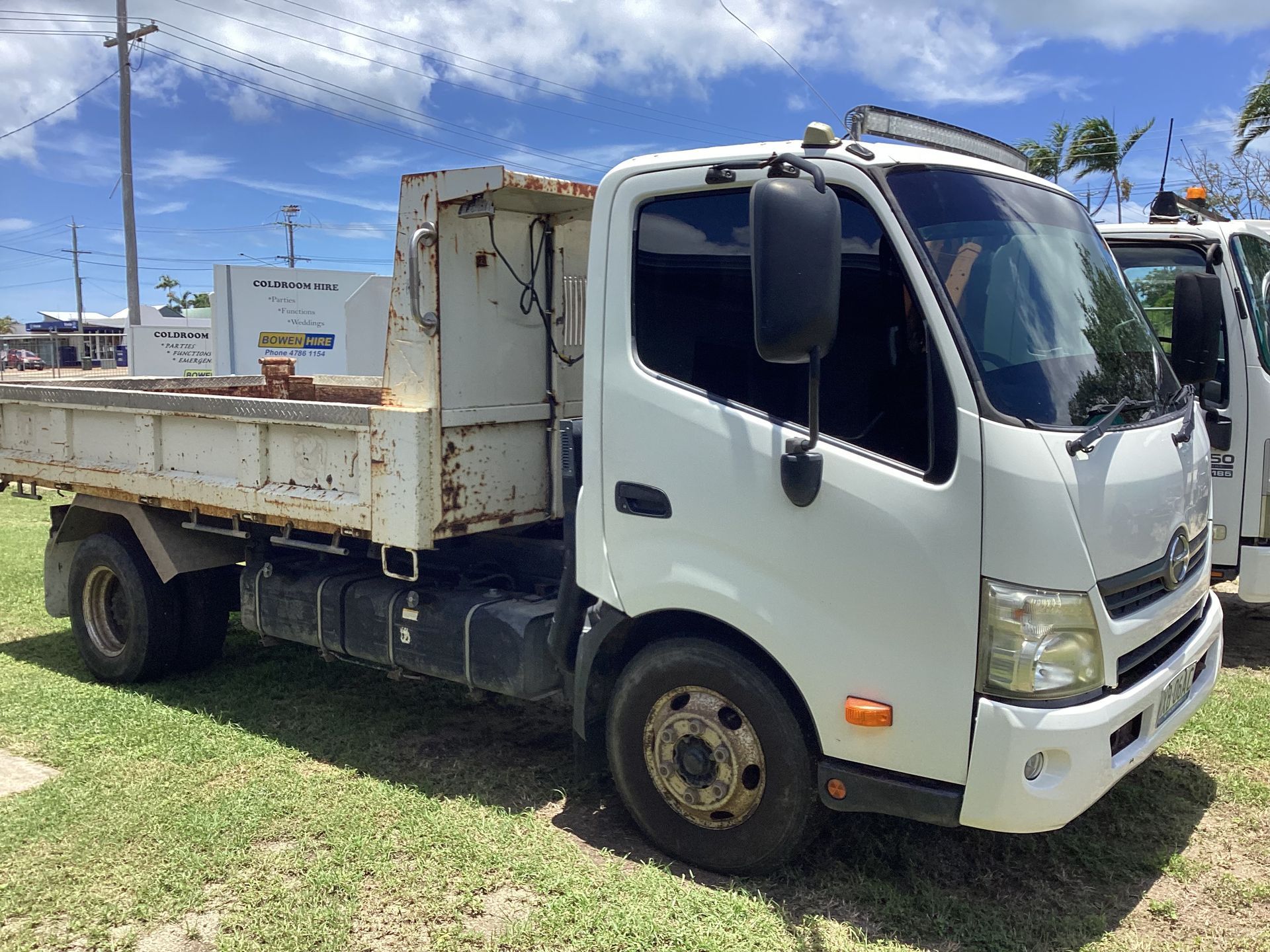 White Flatbed Truck Parked on Grass Under a Bright Blue Sky — Bowen Hire in Bowen, QLD