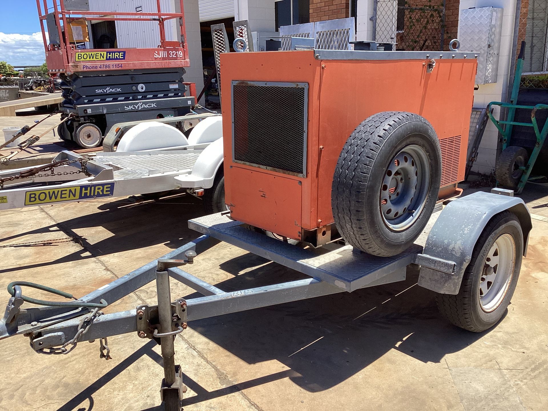 Orange Portable Generator on a Small Trailer in an Outdoor Lot, With a Spare Tire on the Side — Bowen Hire in Bowen, QLD