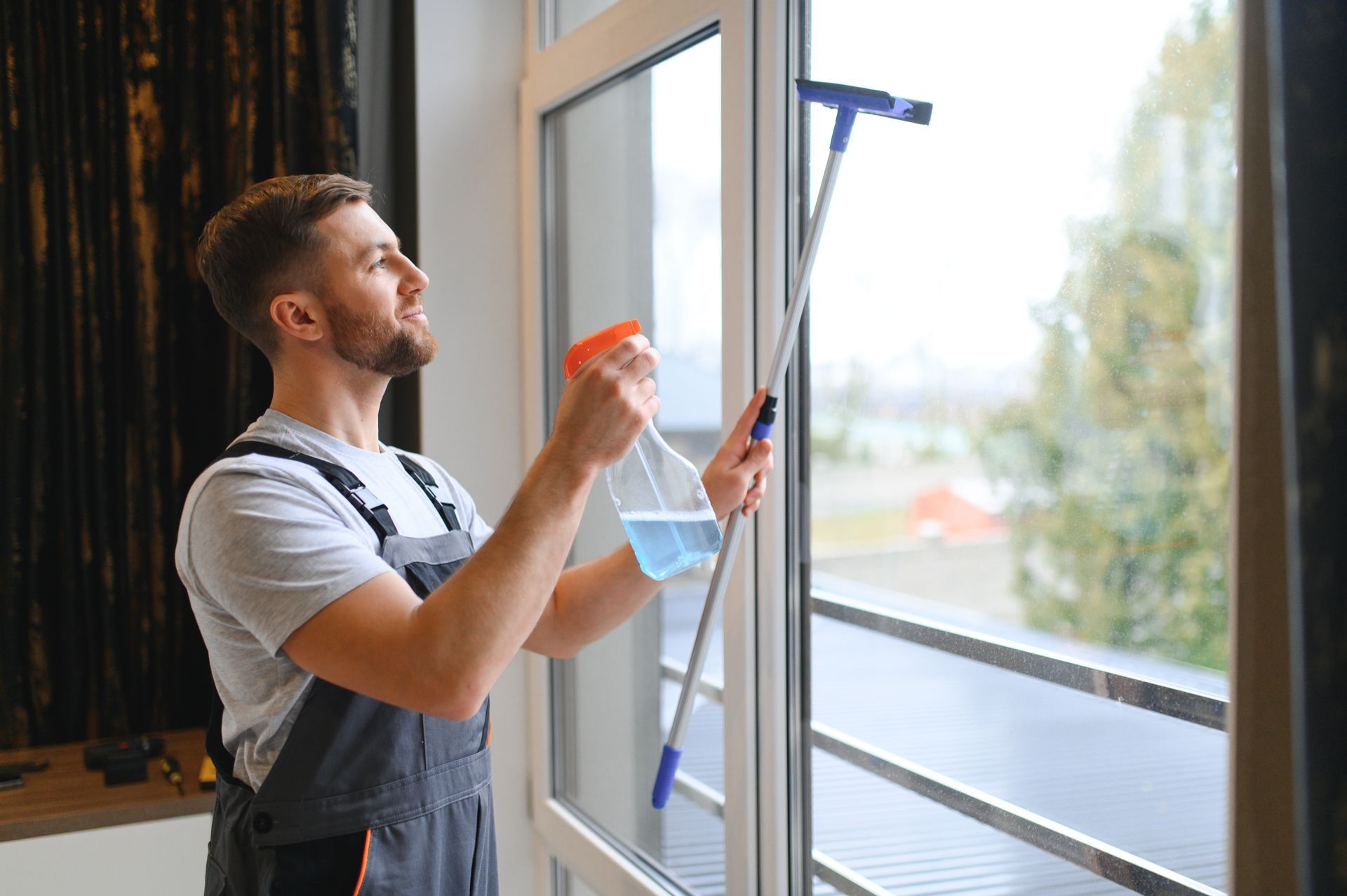 A man is cleaning a window with a spray bottle.