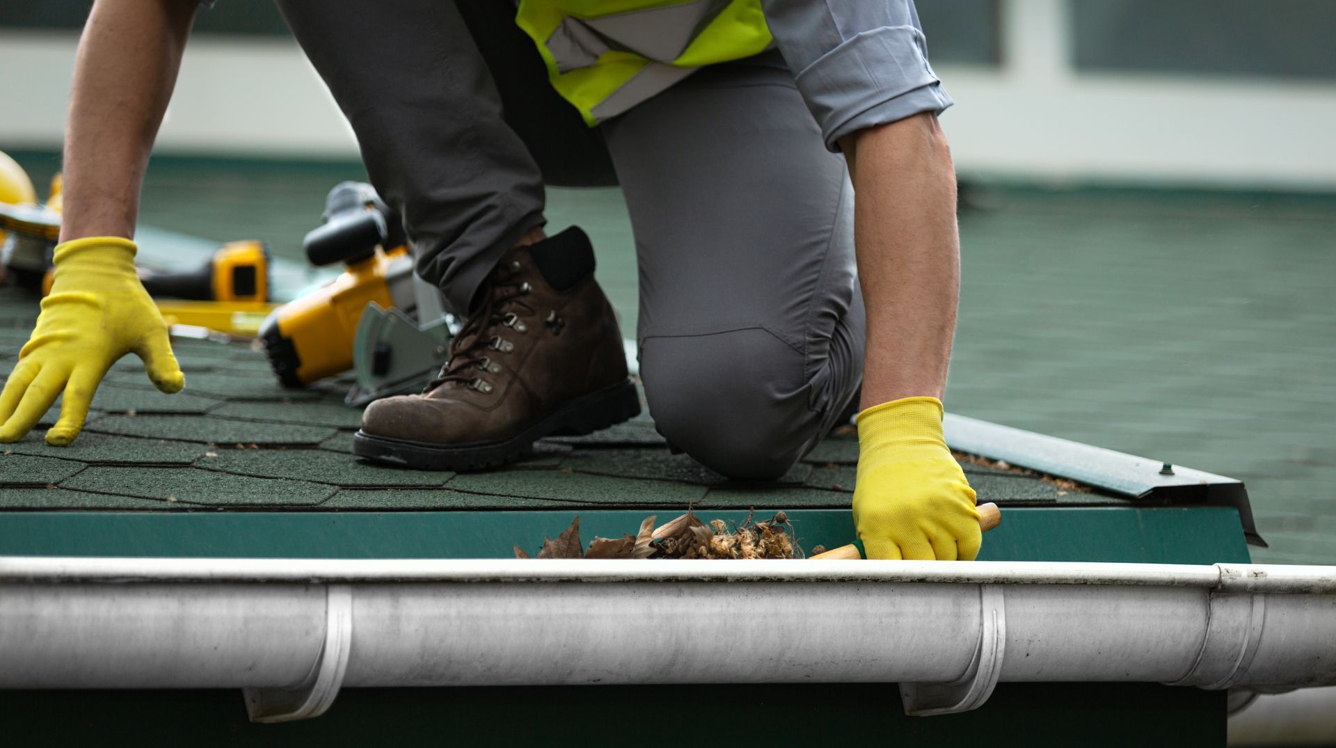 A man wearing yellow gloves is working on a roof.