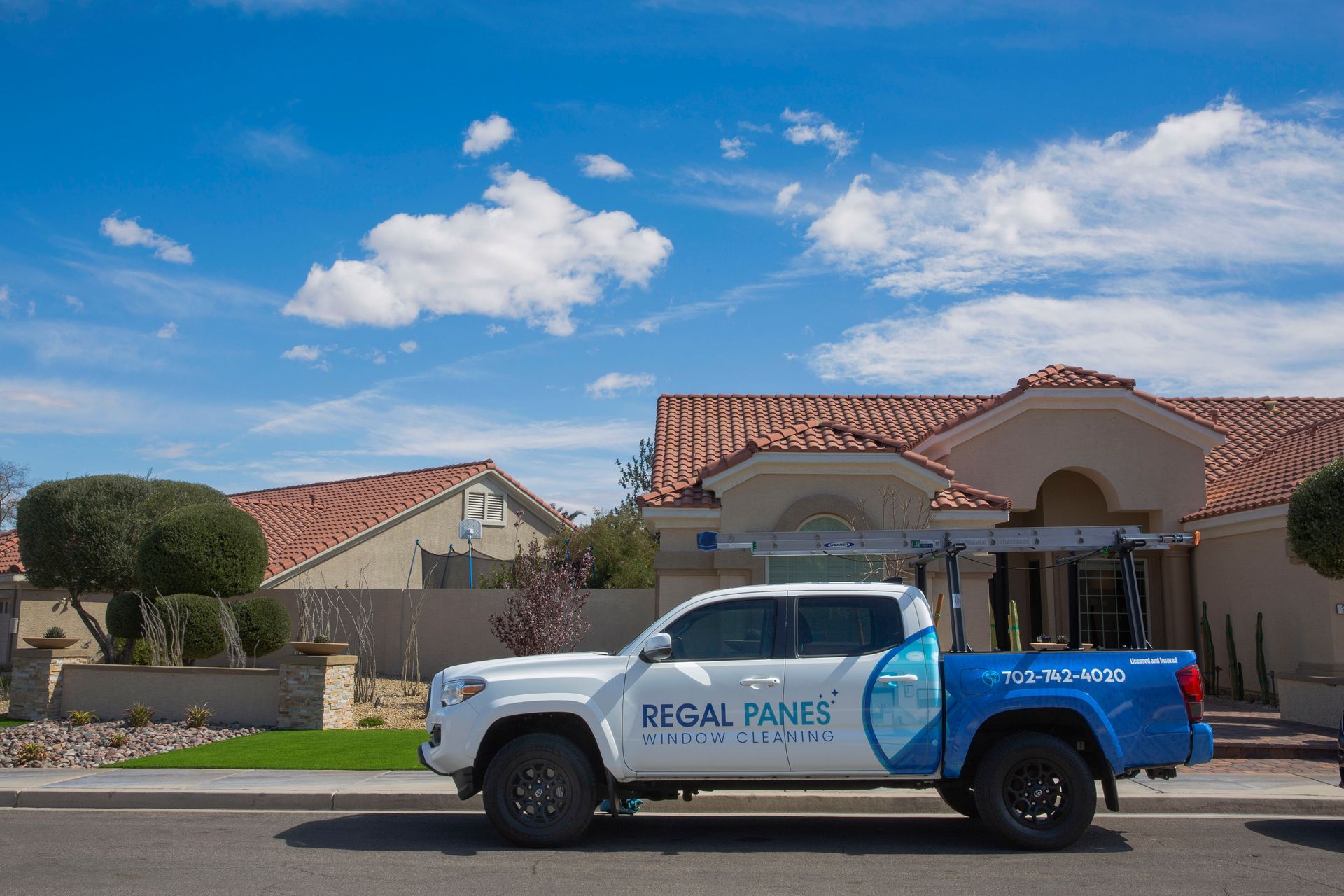 A truck is parked in front of a house on a sunny day.