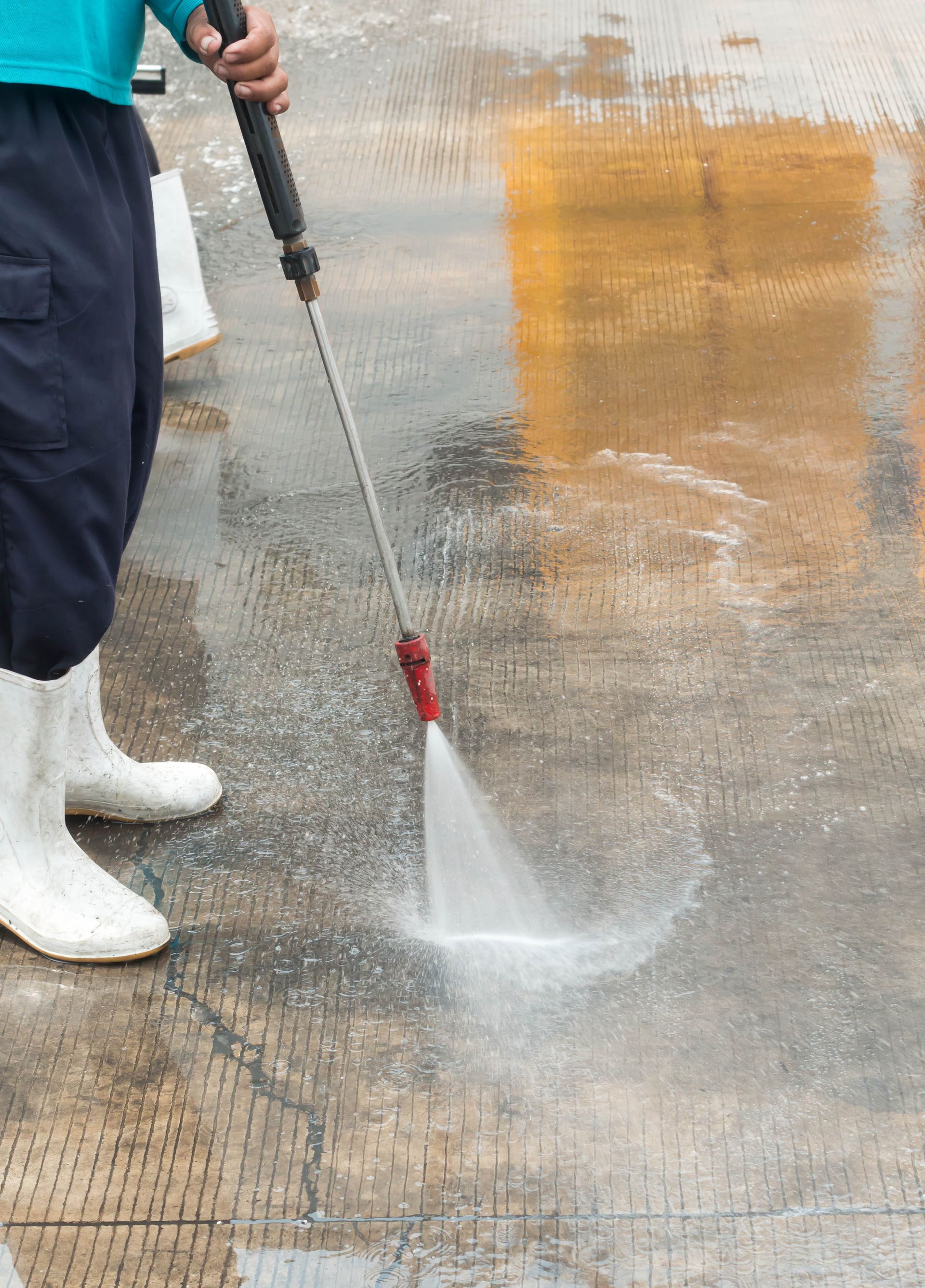 A person is using a high pressure washer to clean a concrete floor.