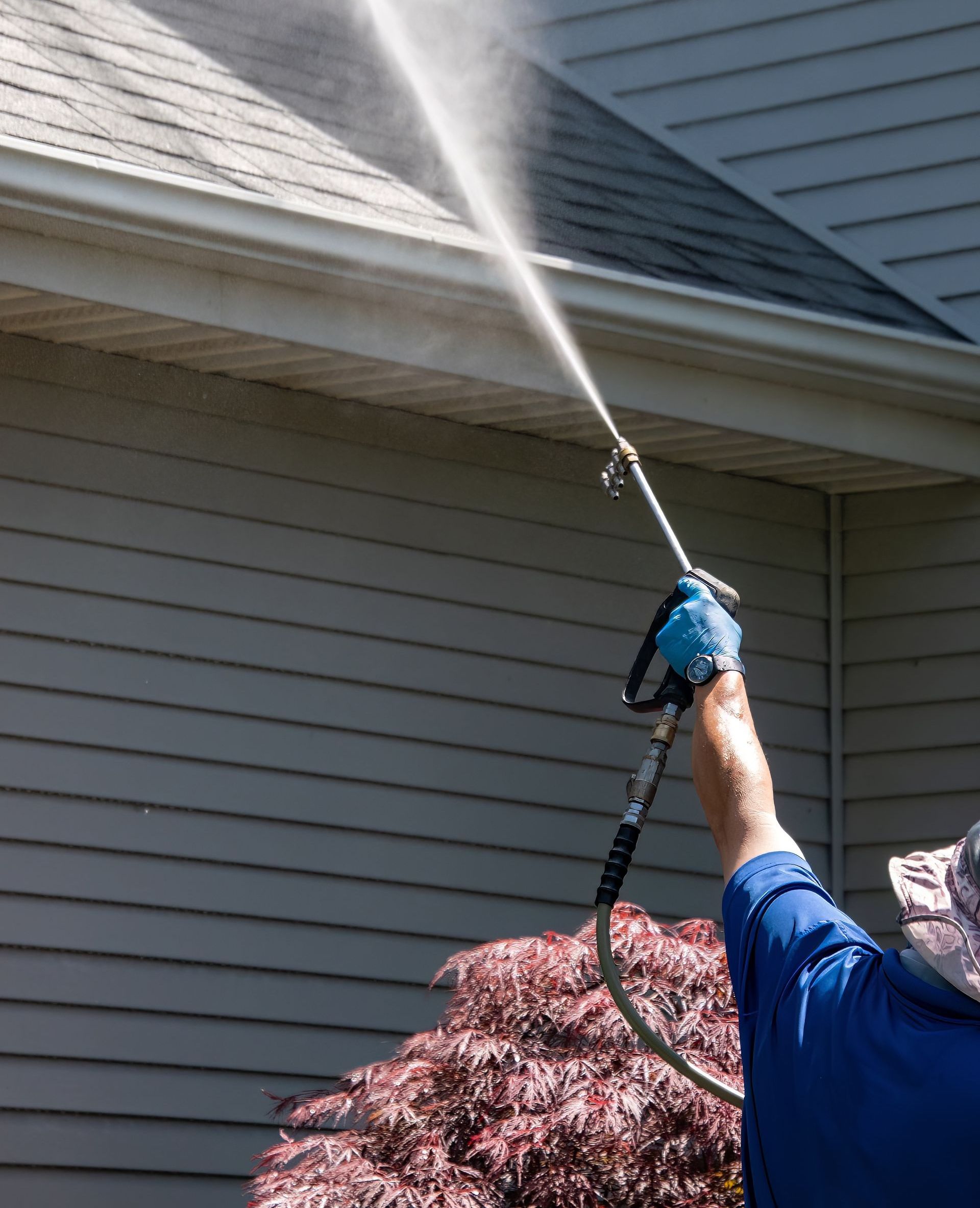 A man is spraying water on the roof of a house.