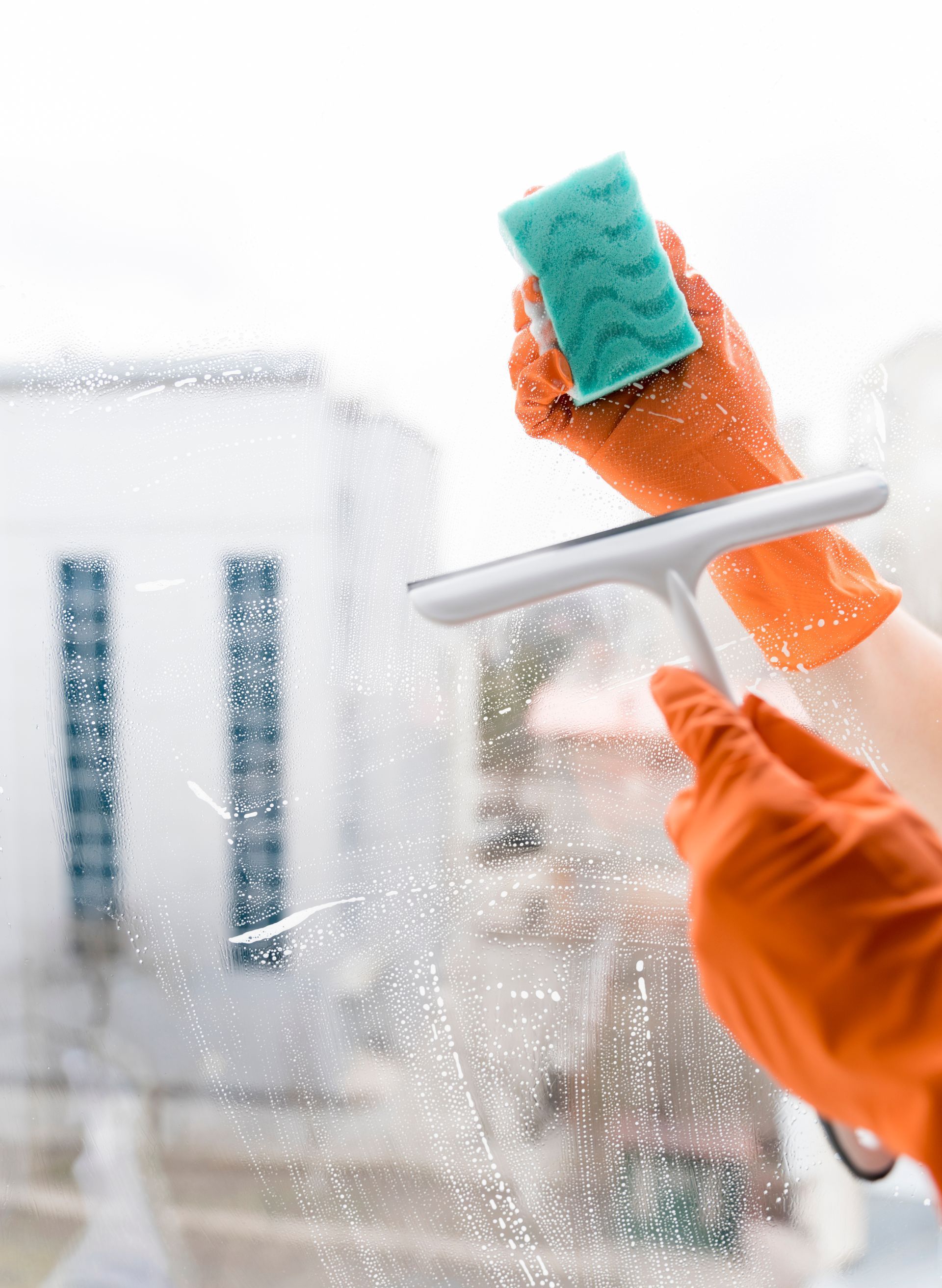 A person is cleaning a window with a cloth and spray bottle.