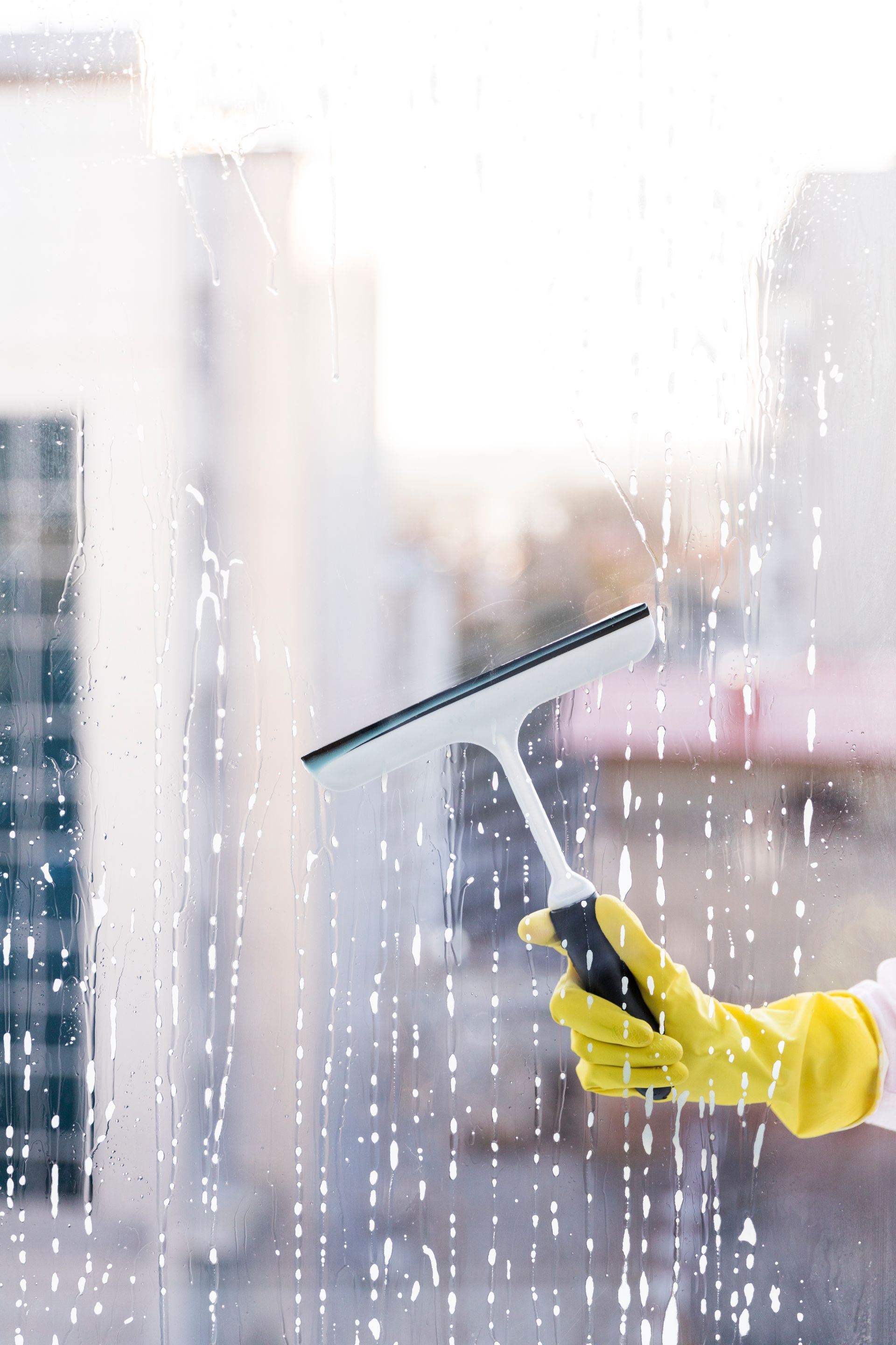 A person is cleaning a window with a squeegee.