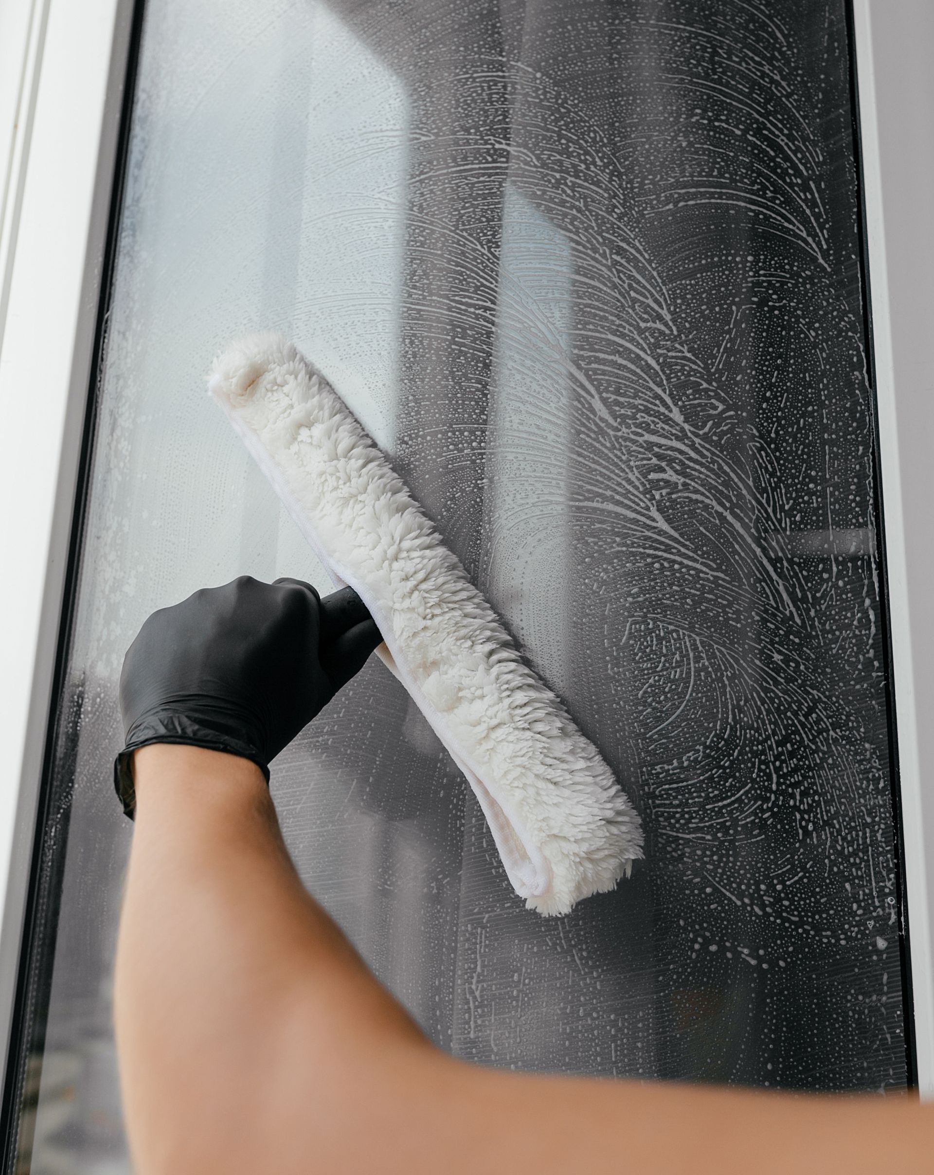 A person is cleaning a window with a brush.