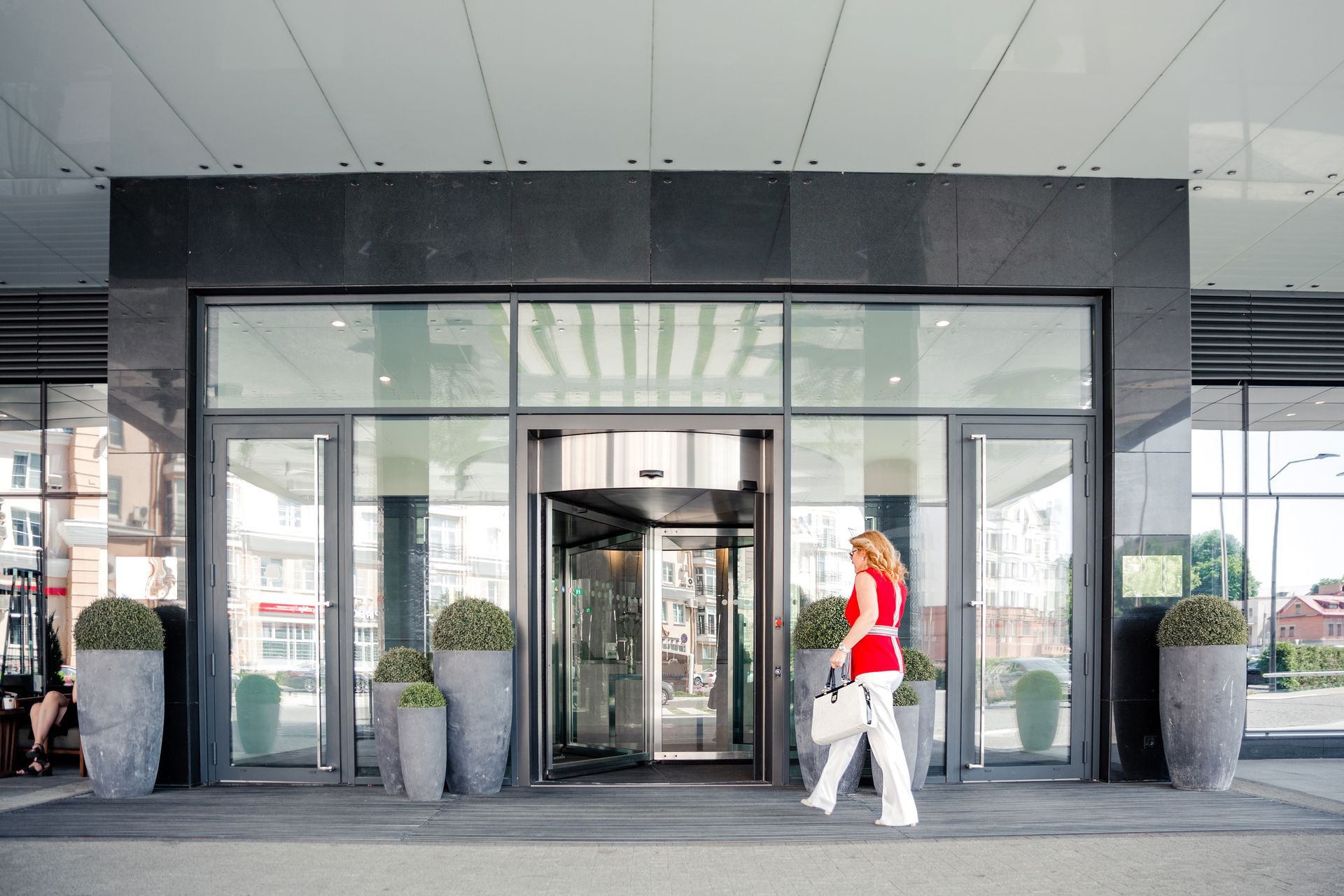 A woman is walking into a building with a revolving door.