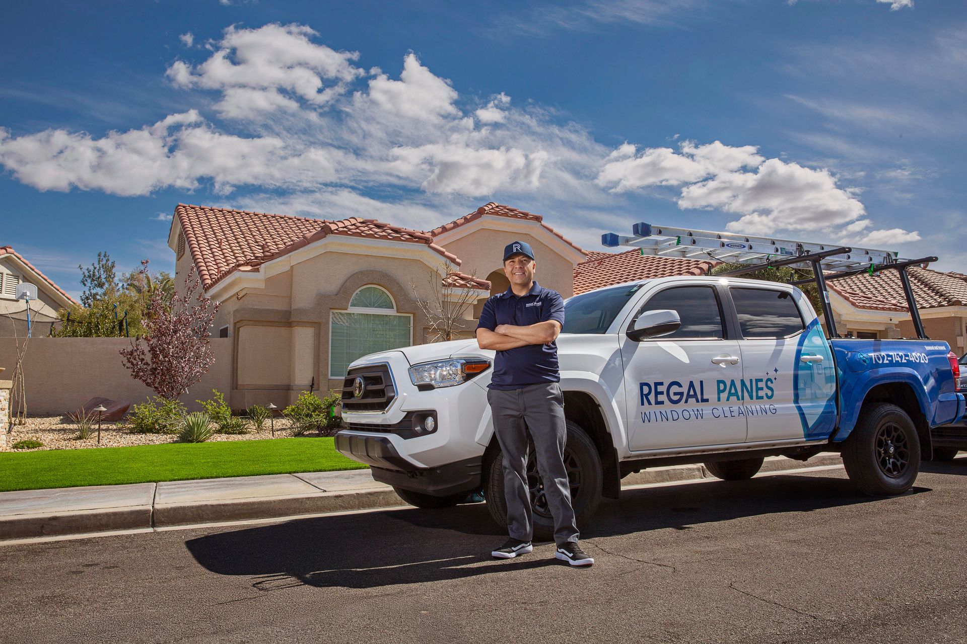 A man is standing next to a truck in front of a house.