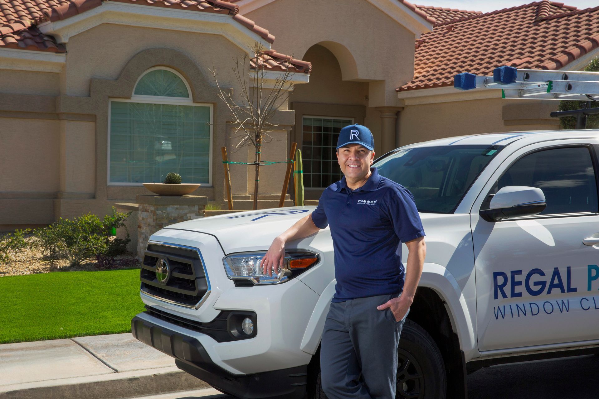 A man is standing next to a white truck in front of a house.