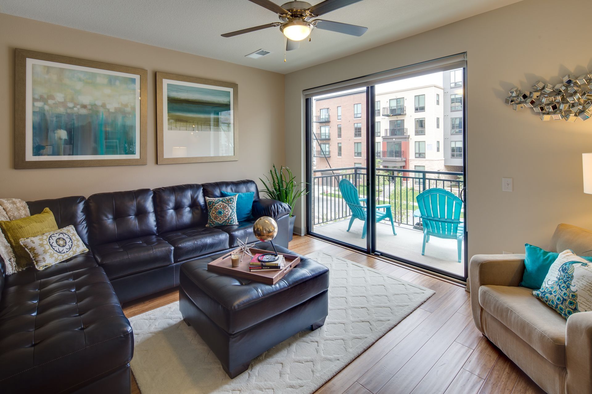 A living room with a couch , ottoman , chairs and a ceiling fan.