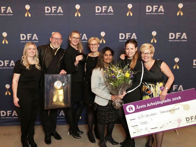 En gruppe mennesker, der står foran en væg, hvorpå der står *dfa*