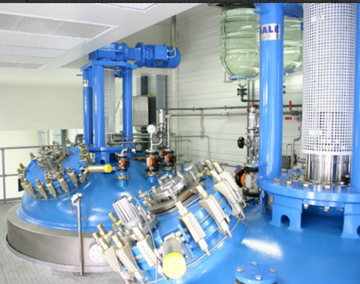 A large blue tank in a factory with the word ale on it