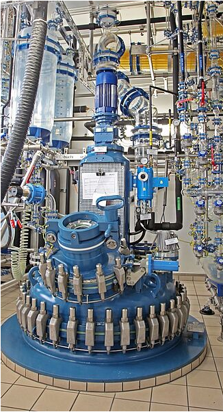 A factory with a lot of stainless steel tanks and pipes.