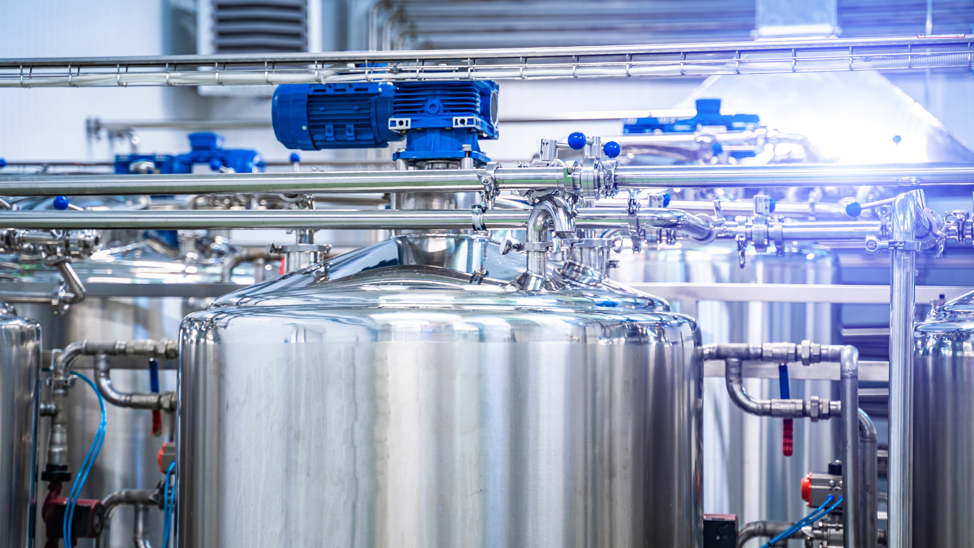 A factory with a lot of stainless steel tanks and pipes.