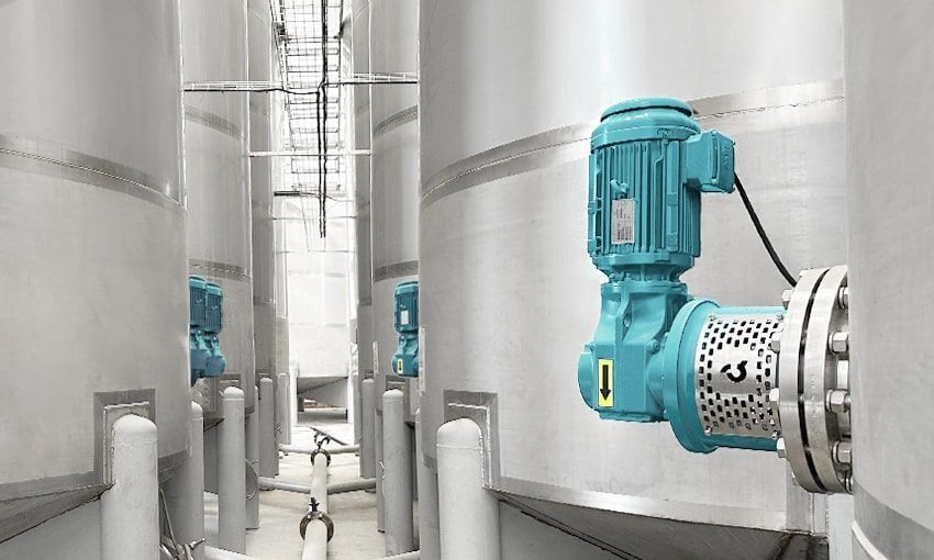A factory with a lot of stainless steel tanks and pipes.