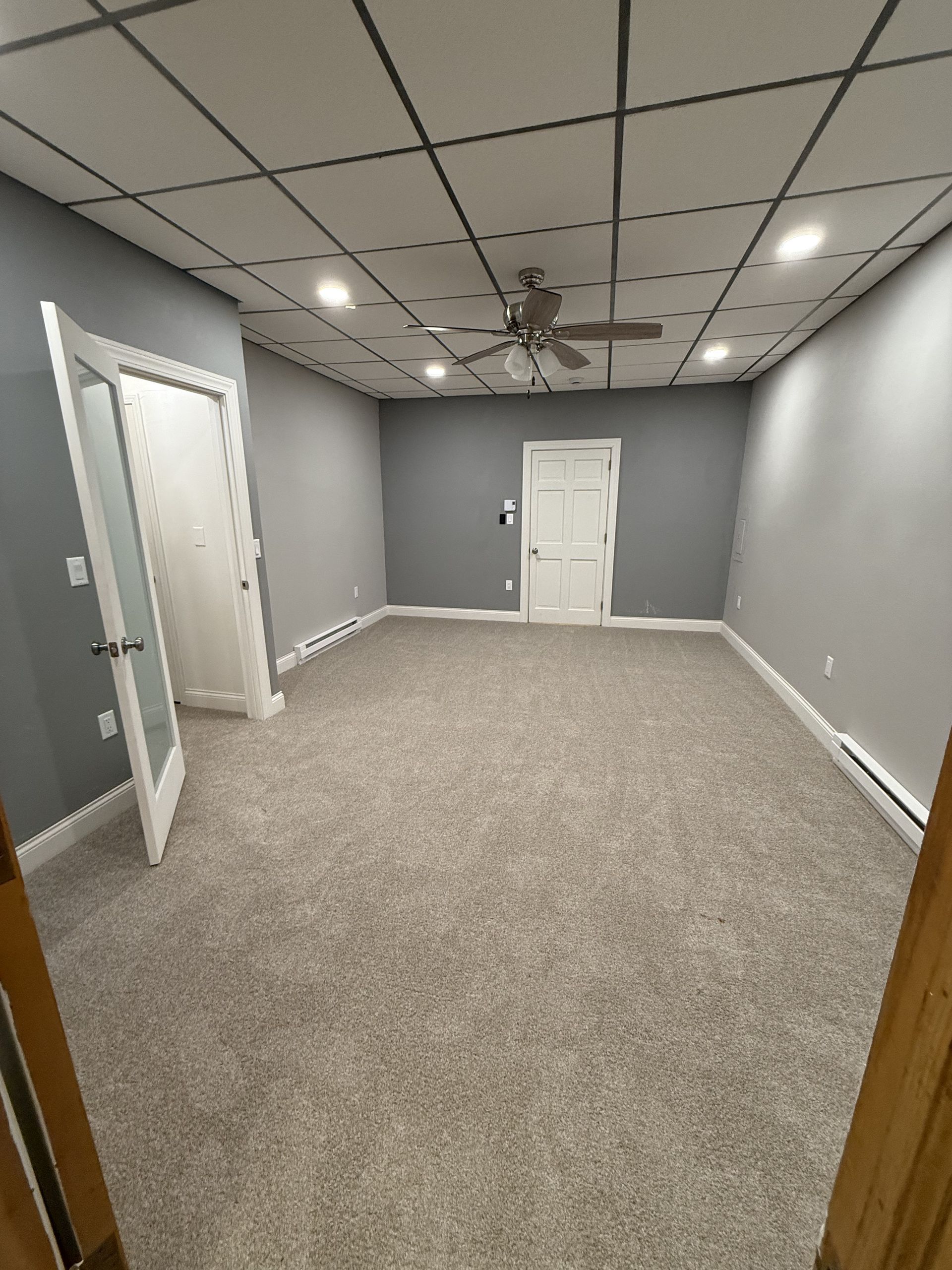 Gray-painted room with neutral carpet, white doors, recessed lighting, and ceiling fan.
