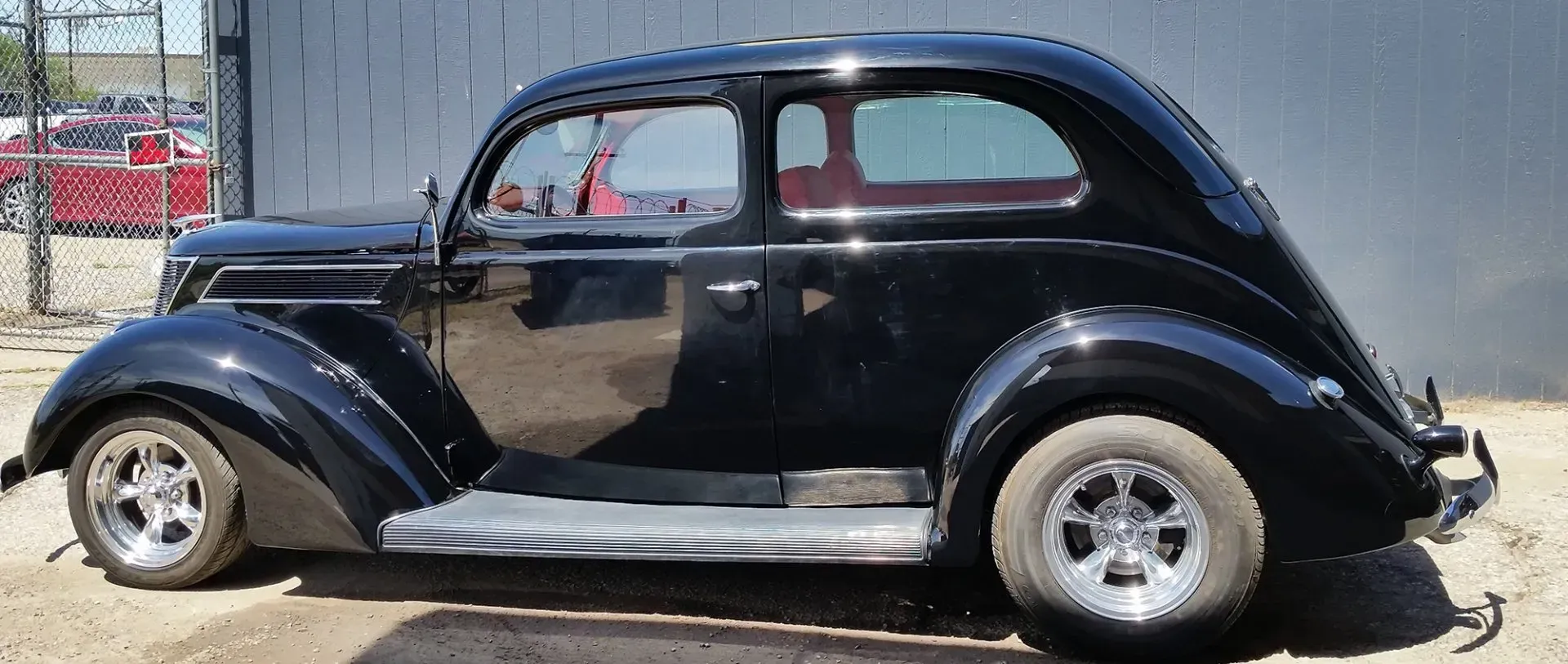 An old black car is parked in front of a building