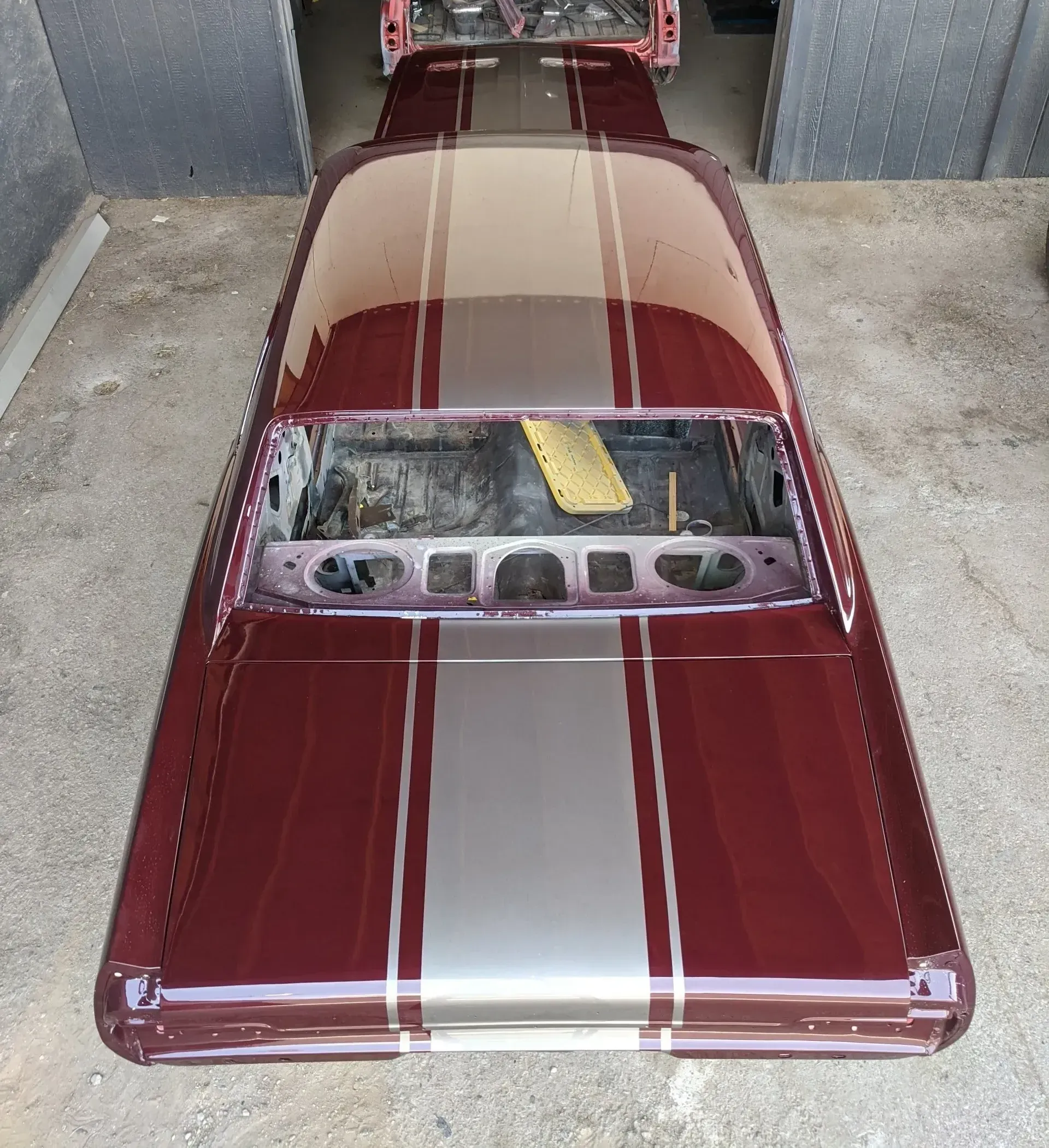 A red car with silver stripes is parked in a garage.