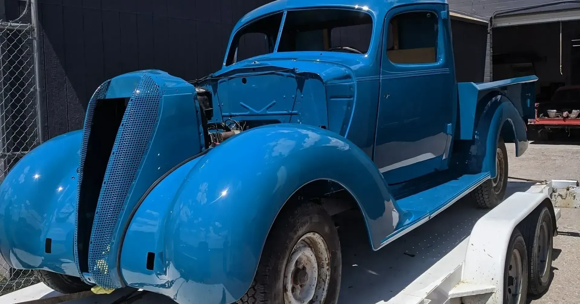 A blue truck is sitting on top of a white trailer.