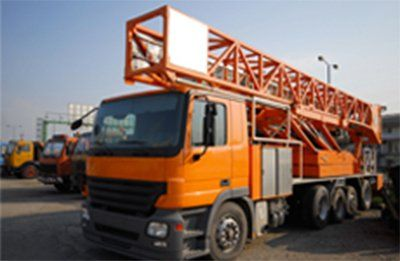 Orange truck with large orange ladder frame on a lot.