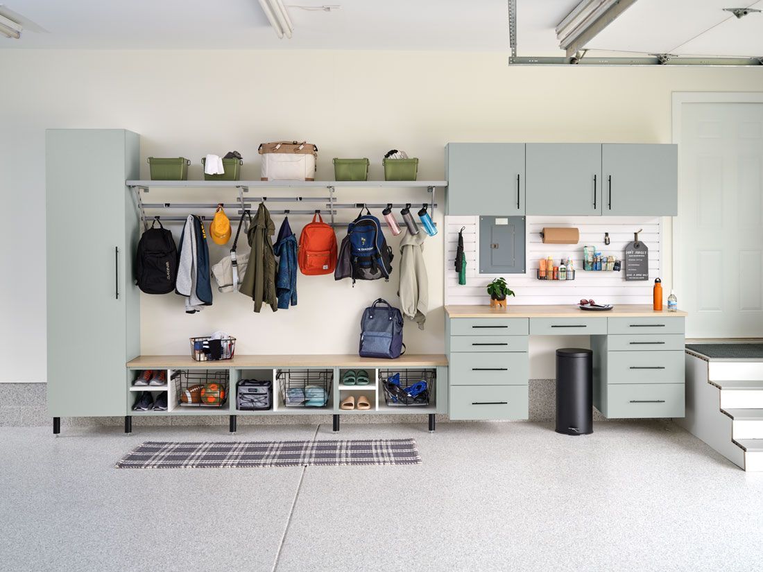 A garage with a desk and clothes hanging on the wall.