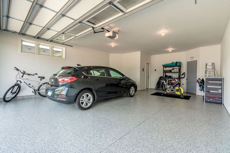A car is parked in a garage next to bicycles.