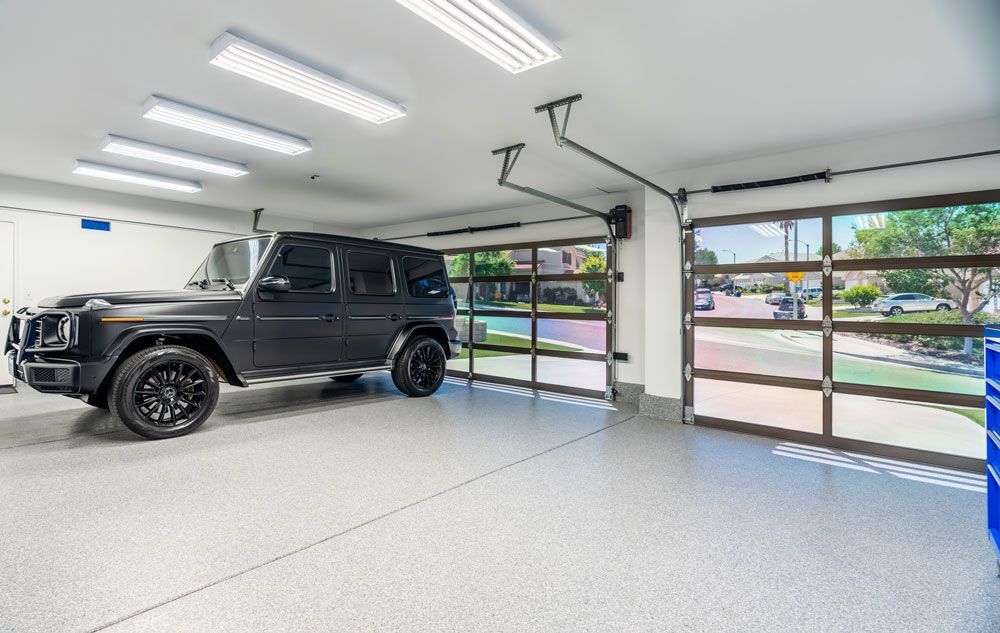 Black Jeep parked in a garage with a clear door and premium concrete coating.
