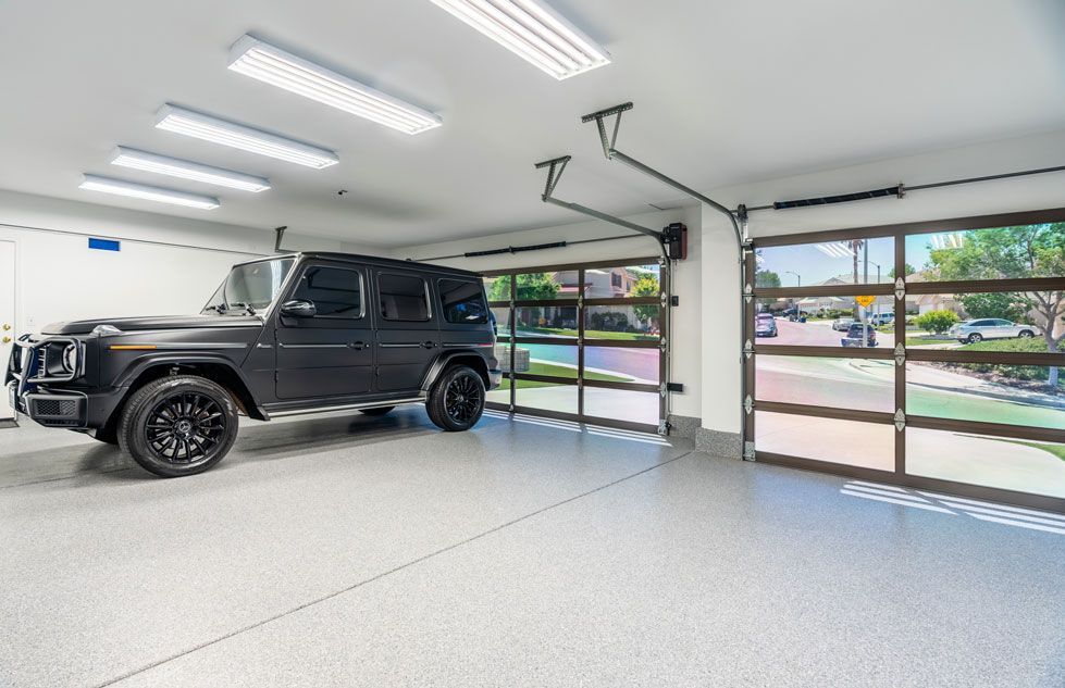 A black jeep is parked in a garage with a glass garage door.