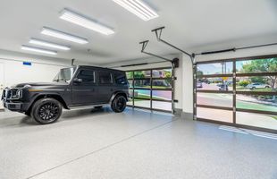 A black jeep is parked in a garage with a glass garage door.