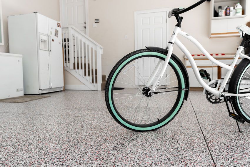 A white bicycle is parked in a garage next to a refrigerator.