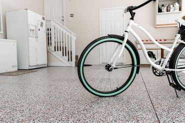 A white bicycle is parked in a garage next to a refrigerator.