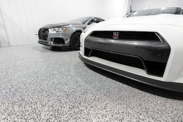 Two cars are parked next to each other in a garage.