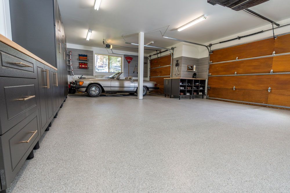 A car is parked in a garage with a garage door open.